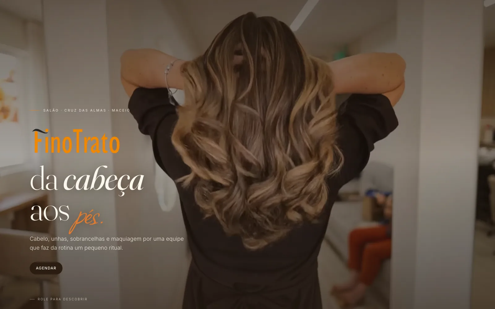 Abertura do site do Fino Trato, com a marca sobre a foto de um atendimento no salão